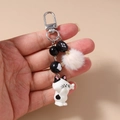Detalle de llavero con cuentas a rayas, colgante de gato y pompón de piel sintética rosa - Gato Corto Blanco y Negro