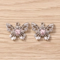 Detailansicht silberner Schmetterlingsanhänger mit rosa Herzkristallen auf Holzhintergrund - Silberrosa