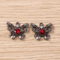 Detail von dunklen Schmetterlingsanhängern mit roten Herzsteinen und Strass für Schmuck DIY - Graurot
