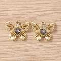 Detailansicht von zwei goldenen Schmetterlingsanhängern mit dunklen Herz-Edelsteinen für DIY - Goldgrau