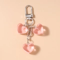 Detailansicht eines rosa Herz-Schlüsselanhängers mit drei Anhängern und Silberkette - Silber