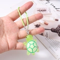 Detail shot of a small green resin turtle charm with vibrant neon green woven lanyard - Green
