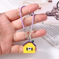 Dettaglio del ciondolo casa giallo con tetto viola su cordino intrecciato e chiusura in metallo - Viola