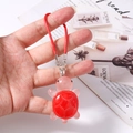 Detail view of cute red turtle phone charm with resin shell held in hand over background - Red