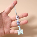 Detalle del colgante para móvil con cuentas azules, cadena gruesa y dije de mariposa - Azul