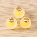 Macro view of three yellow frosted resin ball charms with gold metal rings on a wood background - 10 Pieces Pack / Yellow