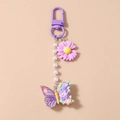 Detalle de llavero de margarita y mariposa púrpura con cadena de perlas suaves - Flor Púrpura Mariposa