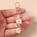 Detail of beaded daisy keychain with pink floral charm held in hand for scale - Pink