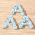 Macro view of light blue resin letter A charms with shimmering iridescent sequins and metal rings - Letter A