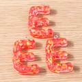 Detailed macro view of resin letter E pendants with red gold glitter for DIY crafts - 5 Pieces / Letter E