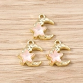 Primer plano de colgantes dorados de estrella y luna con resina rosa sobre fondo madera - Oro Rosa