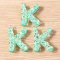Macro detail of three letter K pendants made of resin with mint green iridescent sequins - 5 Pieces / Letter K