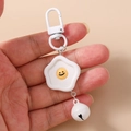 Detalle del llavero de huevo frito con cara sonriente y cascabel blanco en d-ring - Forma de huevo poché / Blanco