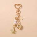 Dettaglio di un portachiavi a cuore dorato con perline e ciondolo a forma di stella - Stile Cuore Stella Marina