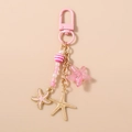 Detalle de llavero de estrella de mar rosa con dijes de esmalte y cuentas a rayas - Rosa