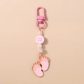 Detail of pink baby footprint charms and faceted beads on a golden keychain pendant - Pink