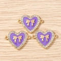 Makro-Detail von herzförmigen Schmuckanhängern mit lila Emaille und goldener Schleife - 10er Pack / Goldviolett