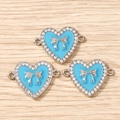 Close-up of heart charms with sky blue enamel, silver bows, and sparkling rhinestones - 10 Pieces Pack / Silver Blue