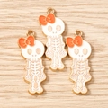 Detailed view of three skull charms with orange bows and gold-plated enamel finish - 10 Pieces Pack / Gold White Orange