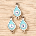 Detailansicht von drei blauen Evil Eye Anhängern in Tropfenform auf hellem Holzhintergrund - 10 Stück / Silber-Blau