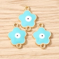 Dettaglio di tre ciondoli a fiore di ciliegio placcati in oro con centro malocchio - Oro Blu
