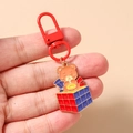Dettaglio di un ciondolo a forma di orsetto con moschettone rosso su un portachiavi - Orso Del Cubo Di Rubik