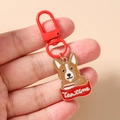 Detailansicht eines süßen Corgi-Hunde-Schlüsselanhängers mit rotem Metallring in der Hand - Hund im Getränke-Stil