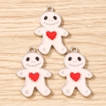 Close-up of three gingerbread man enamel charms with red hearts on a wooden surface - 10 Pieces Pack / Pink