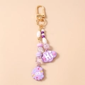 Detalle del llavero de cuentas moradas con colgante nube Hi y charm galleta m en dorado - Morado