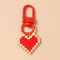 Detail of red 8-bit pixel heart keychain with metallic U-shaped hook and gold edges - Red