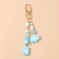 Detalle de llavero con cuentas, dijes de nube azul Hi y galleta m con cierre dorado - Azul
