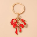 Dettaglio portachiavi dorato con ciondolo rosa LOVE, fiocco rosso e scarpa con strass - Rosso