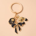 Detail of metal keychain with black rose pendant, golden bow, and rhinestone ballet shoes - Black