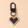 Detail of pixel heart keychain with black matte carabiner on a soft pink background - Black