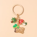 Detalle del llavero de playa de esmalte dorado con palmera y amuleto de hongo rojo - Champiñón Rojo Y Palmera