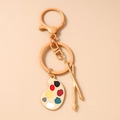 Macro view of gold artist palette and crossed paint brushes on artistic keychain - Light Coffee