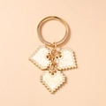 Detail of pixel heart keychain with white enamel pattern and golden metal links - White