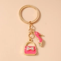Detail van gouden sleutelhanger met roze emaille naaldhak en handtas bedeltjes - Rozerood