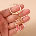 Dettaglio del portachiavi musicale dorato con ciondoli a forma di chitarra e arpa rosa - Arpa Rosa
