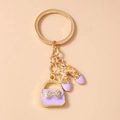 Detail van paarse emaille handtas en balletschoen hangers met kristallen op gouden sleutelhanger - Paars