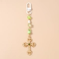 Detail of baroque gold cross keychain with green gemstone and striped beads accent - Gold Cross