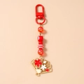 Detail of red beaded keychain with cherry blossom fan pendant and gold-tone metal hardware - Red