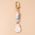 Detail of cute dinosaur keychain with pastel beads and a golden metal clasp - Pink Dinosaur
