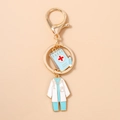 Dettaglio portachiavi a tema medico con ciondoli a forma di taccuino e camice bianco - Cartella Clinica Blu Camice Bianco