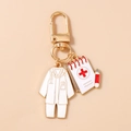 Close-up of doctor themed metal keychain with lab coat and notepad charms on gold ring - White Medical Chart Uniform Style