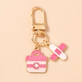 Detail showing pink first aid kit and bandage enamel charms on a gold keychain - Rose Red Kit Band-Aid Style