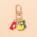 Detailed view of red fire extinguisher and yellow boots enamel charms on golden keychain - Extinguisher and Boot
