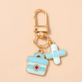 Detail of medical keychain featuring gold lobster clasp with blue first aid kit and bandage charms - Blue Kit Band-Aid Style