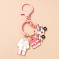 Detailed close-up of pink medical charms including nurse uniform and ambulance keychain - Pink