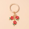 Close-up of golden keychain featuring three red enamel roses with sparkling white crystals - Red